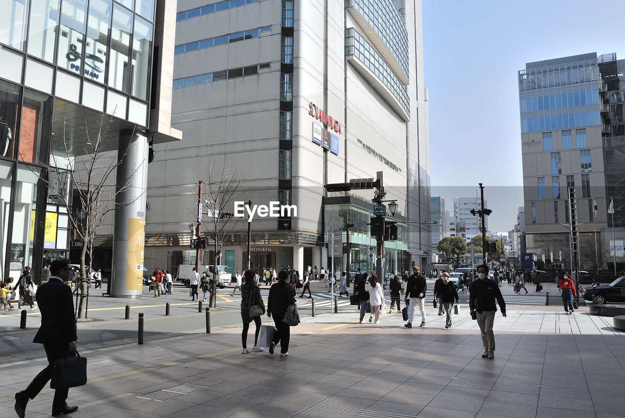 PEOPLE WALKING ON STREET AGAINST BUILDINGS IN CITY