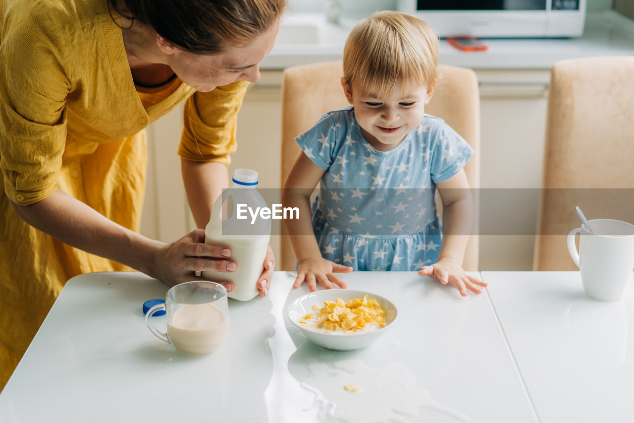 Little toddler daughter spilled milk on the table.