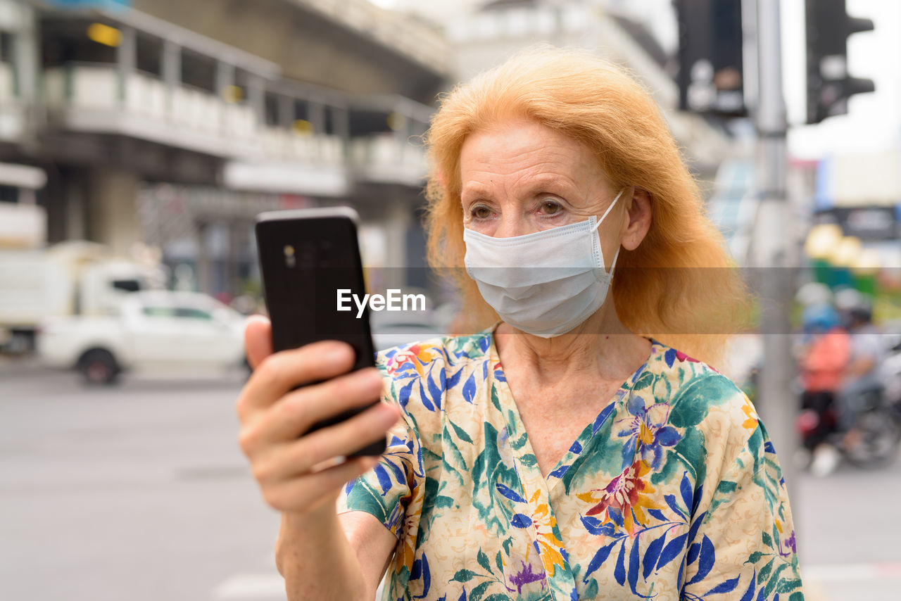 Portrait of woman holding mobile phone in city