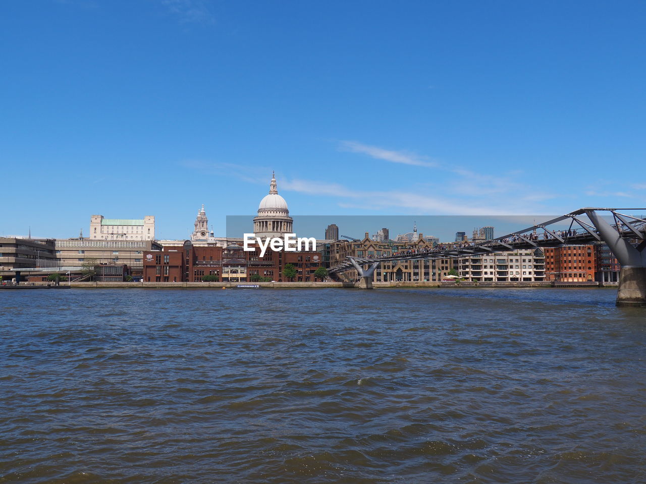 View of buildings by river against sky in city