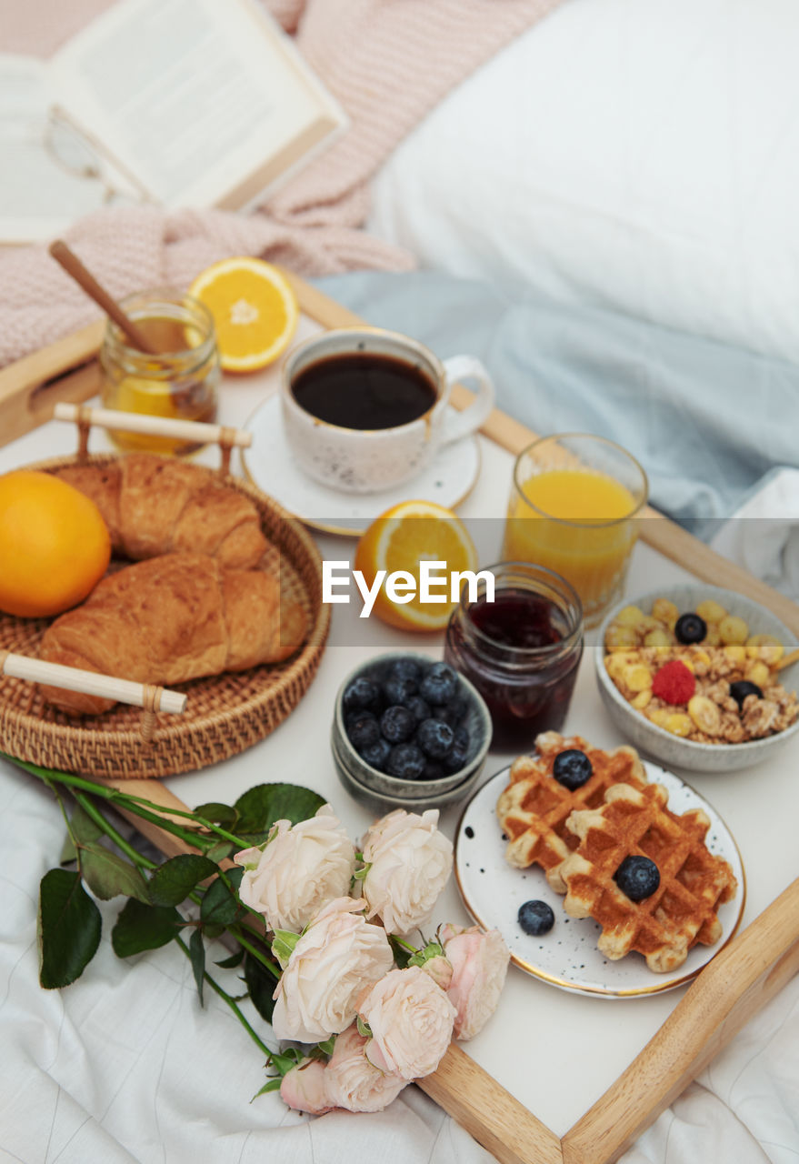 Romantic breakfast with coffee, waffles, orange juice and rose flowers.