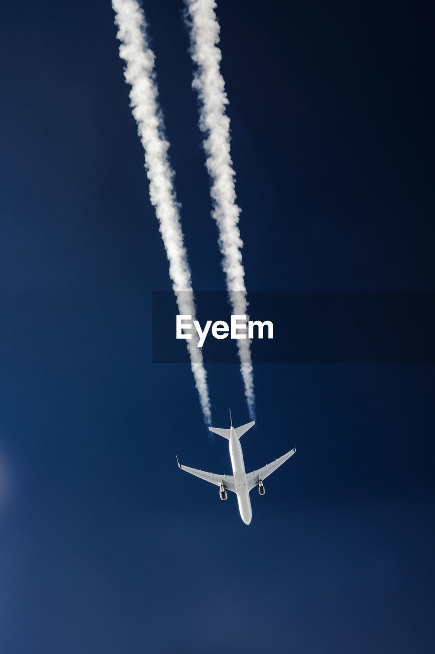 Low angle view of airplane flying against blue sky