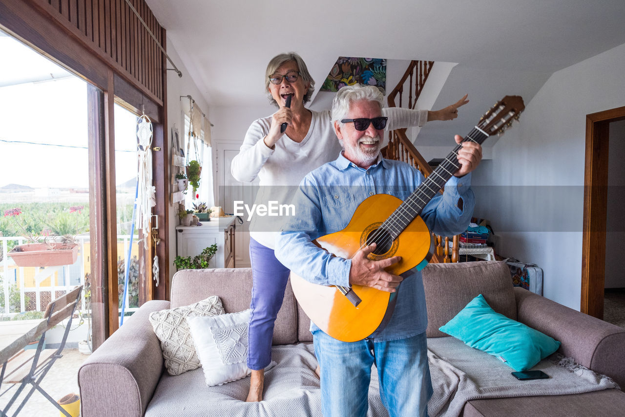 young man playing guitar while sitting at home