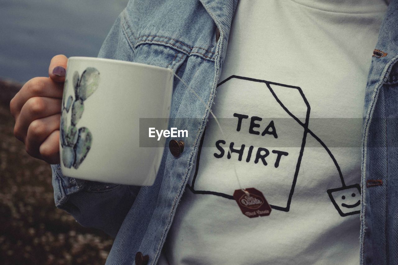 Midsection of woman holding tea cup with text on t-shirt