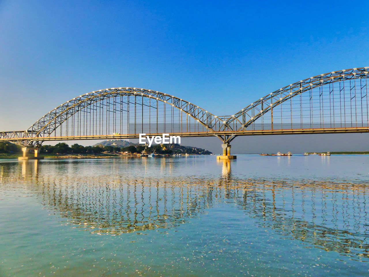 Bridge over river against clear blue sky