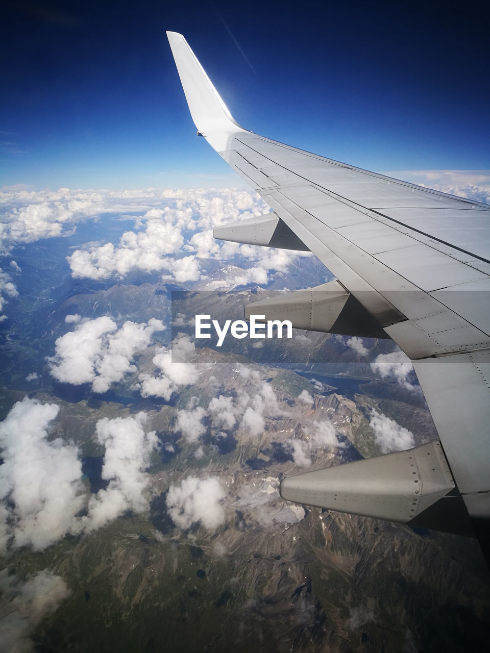Cropped image of airplane flying over mountains against clear sky