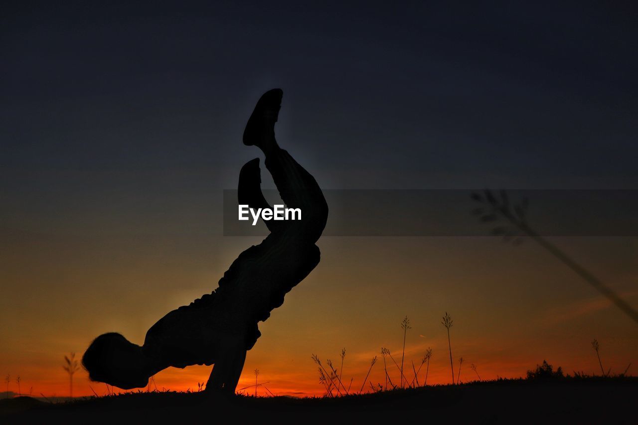 Silhouette man exercising on field against sky during sunset