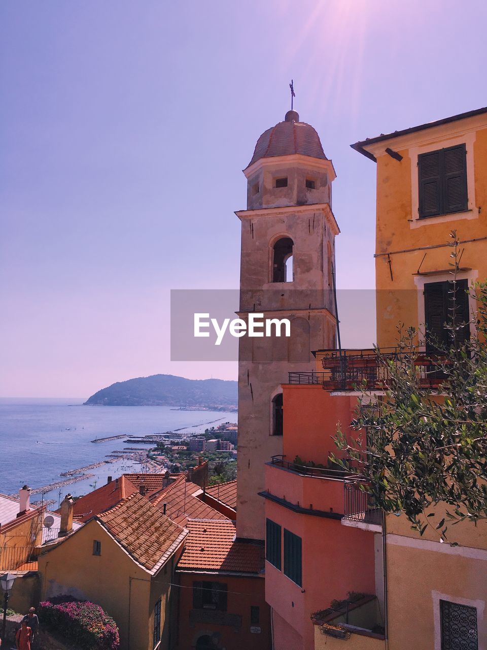 Italian village by the mediterranean sea, bell tower, cityscape, horizon, rooftops, colorful facades 