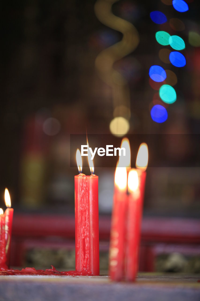 CLOSE-UP OF CANDLES BURNING IN TEMPLE