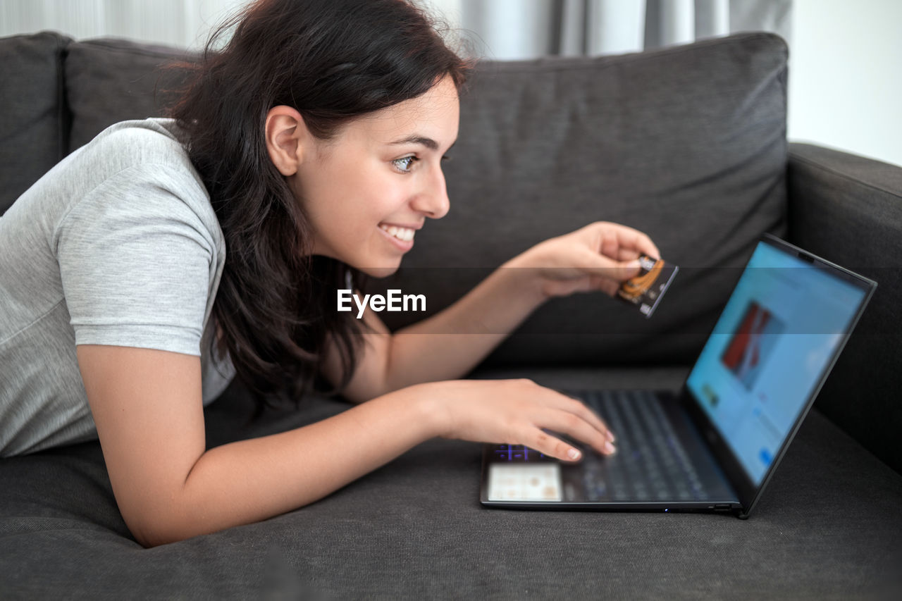 side view of young woman using laptop at home