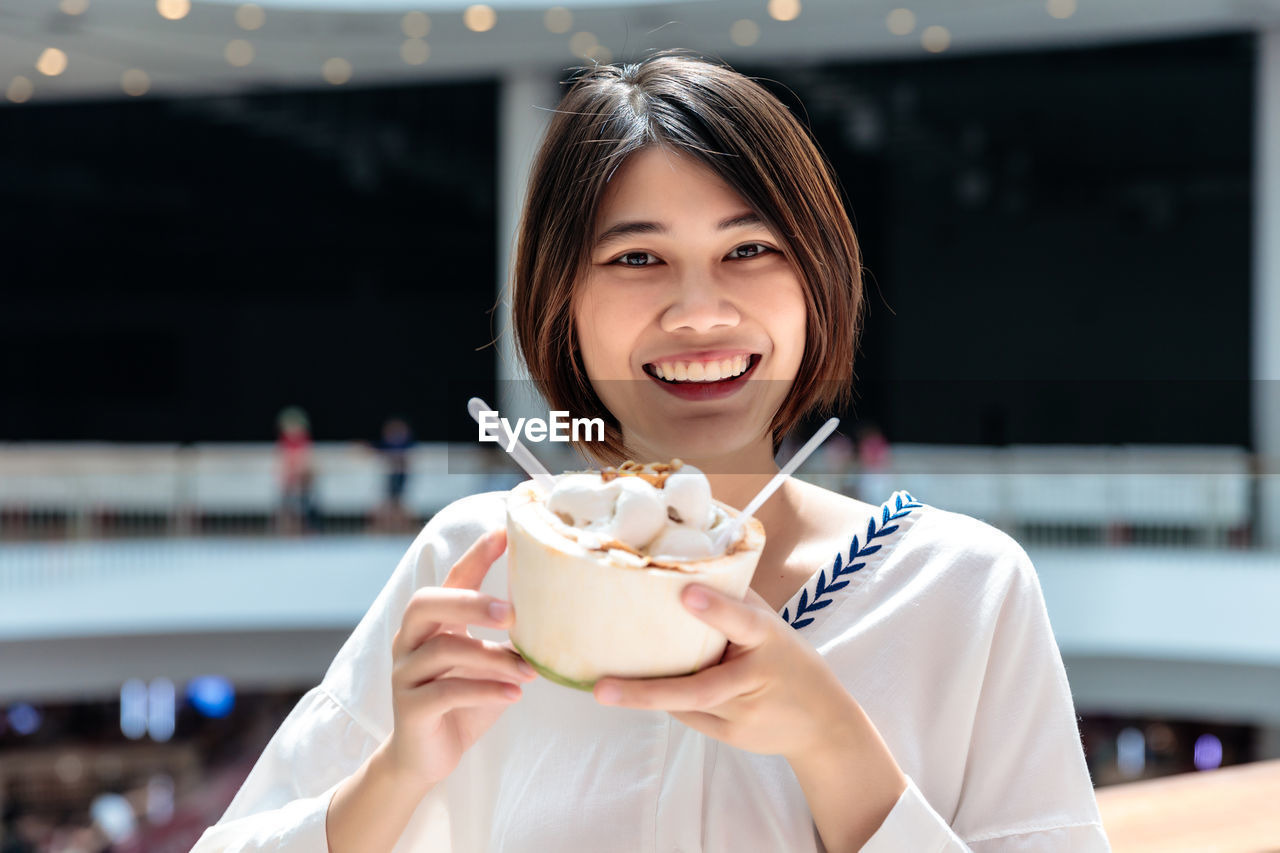 Coconut ice cream in coconut shell in woman hands enjoying eating, thailand street food