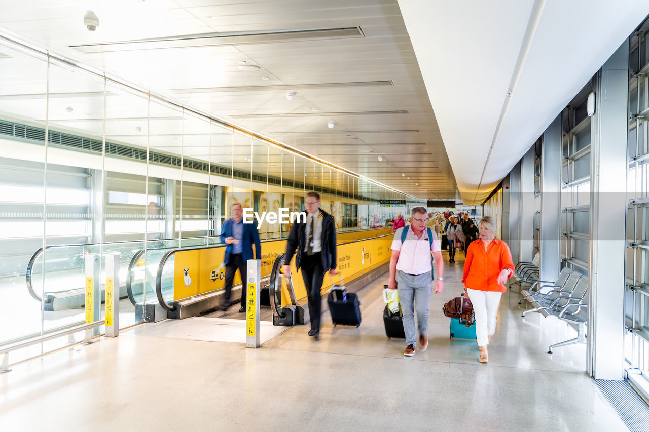 GROUP OF PEOPLE WALKING ON ESCALATOR IN ILLUMINATED UNDERGROUND