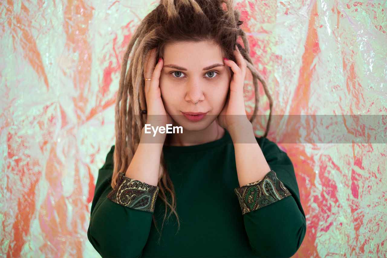 Portrait of beautiful young woman standing against wall