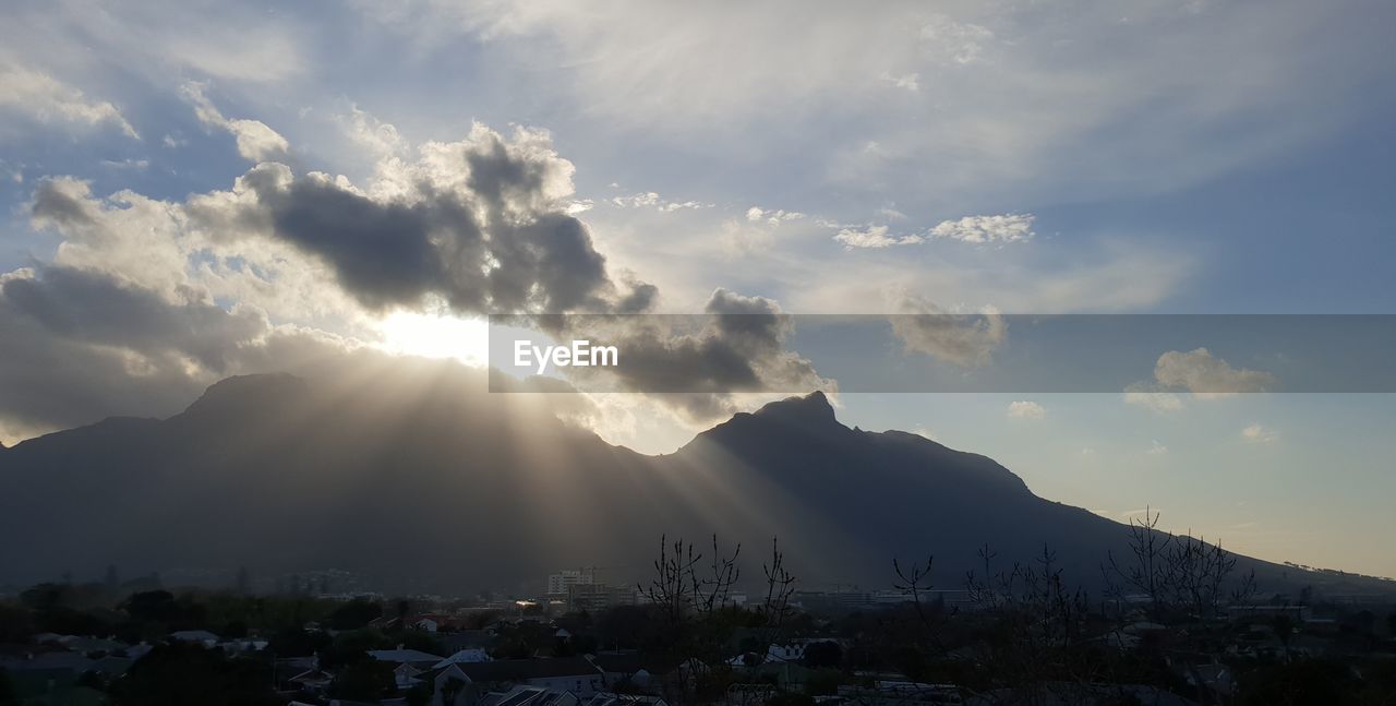 Sunlight streaming through clouds over mountain