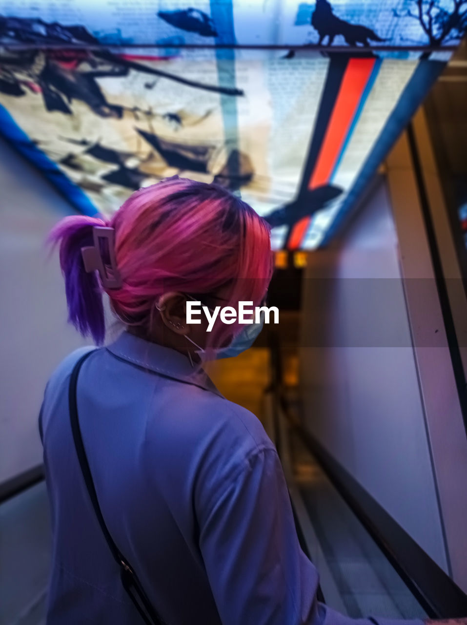 Side view of young woman going down through the escalator.