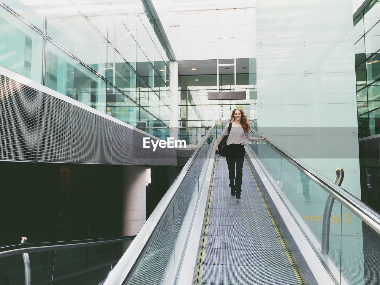 Young woman walking on moving walkway in building
