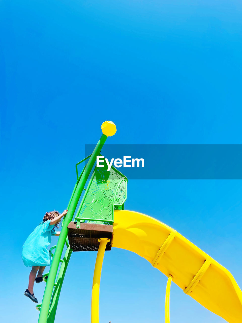 Low angle view of playground slide against clear blue sky