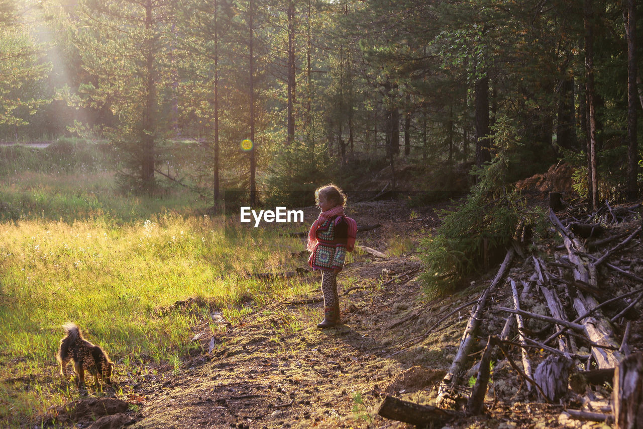 Little girl in casual clothes walks in the taiga forest