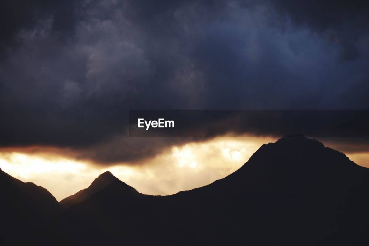 SILHOUETTE OF MOUNTAIN AGAINST CLOUDY SKY