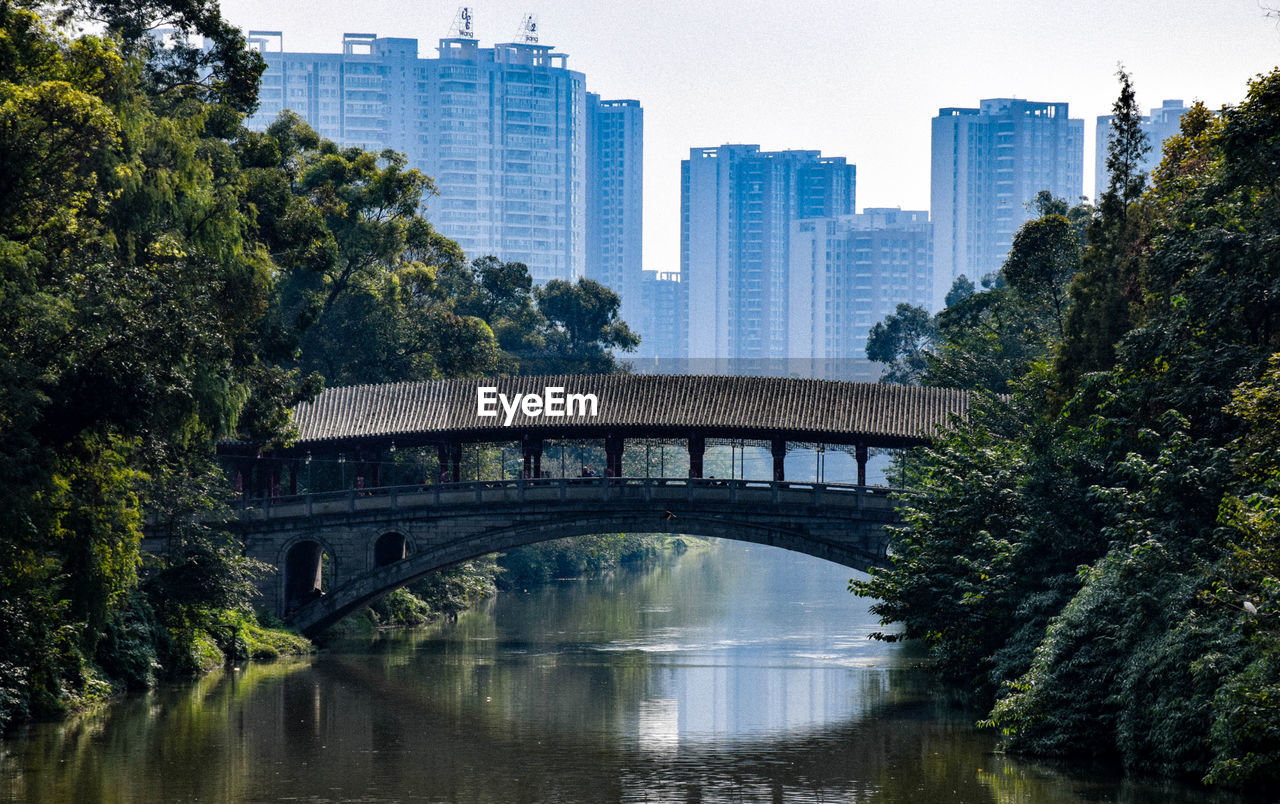 Bridge over river in city against sky