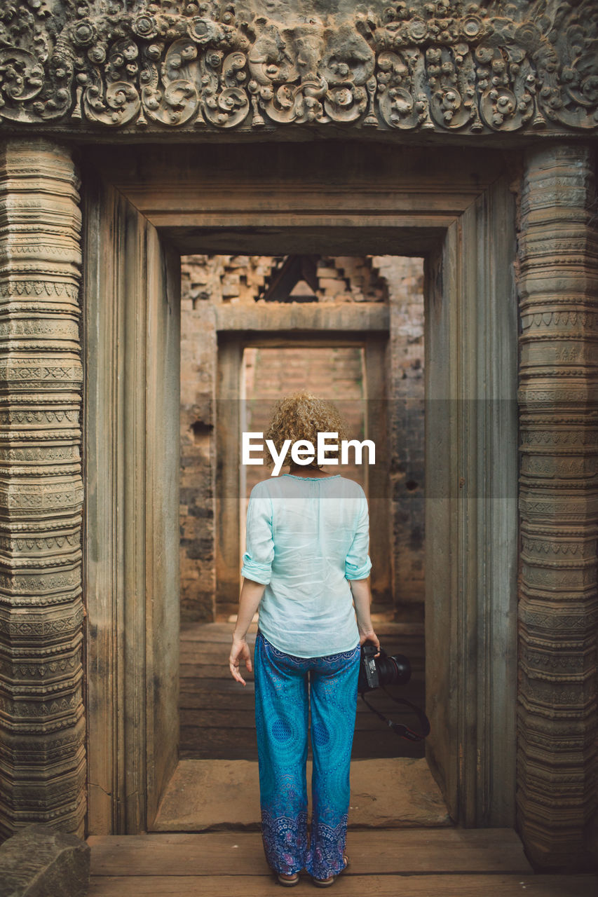 Rear view of woman standing at old ruin doorway