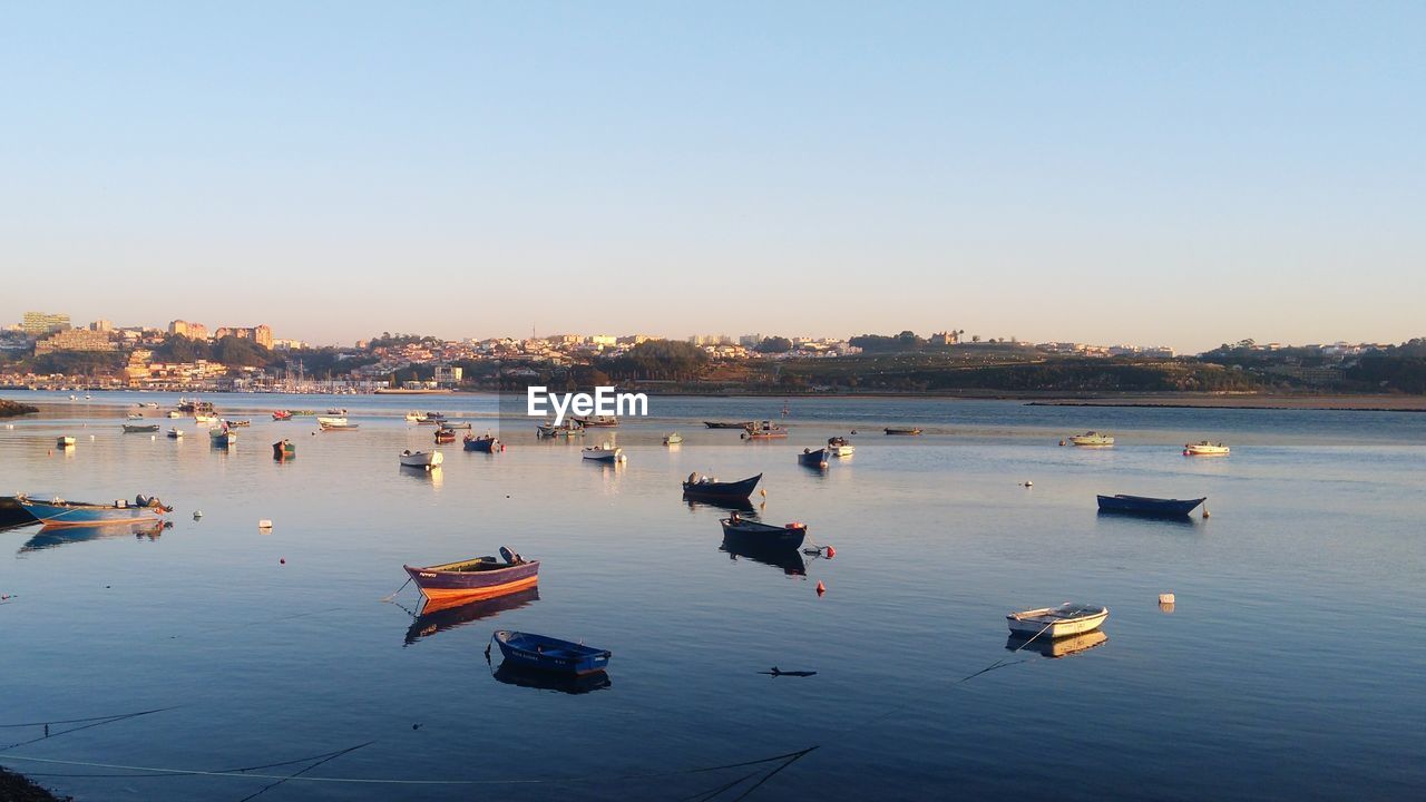 BOATS MOORED IN WATER AGAINST CLEAR SKY