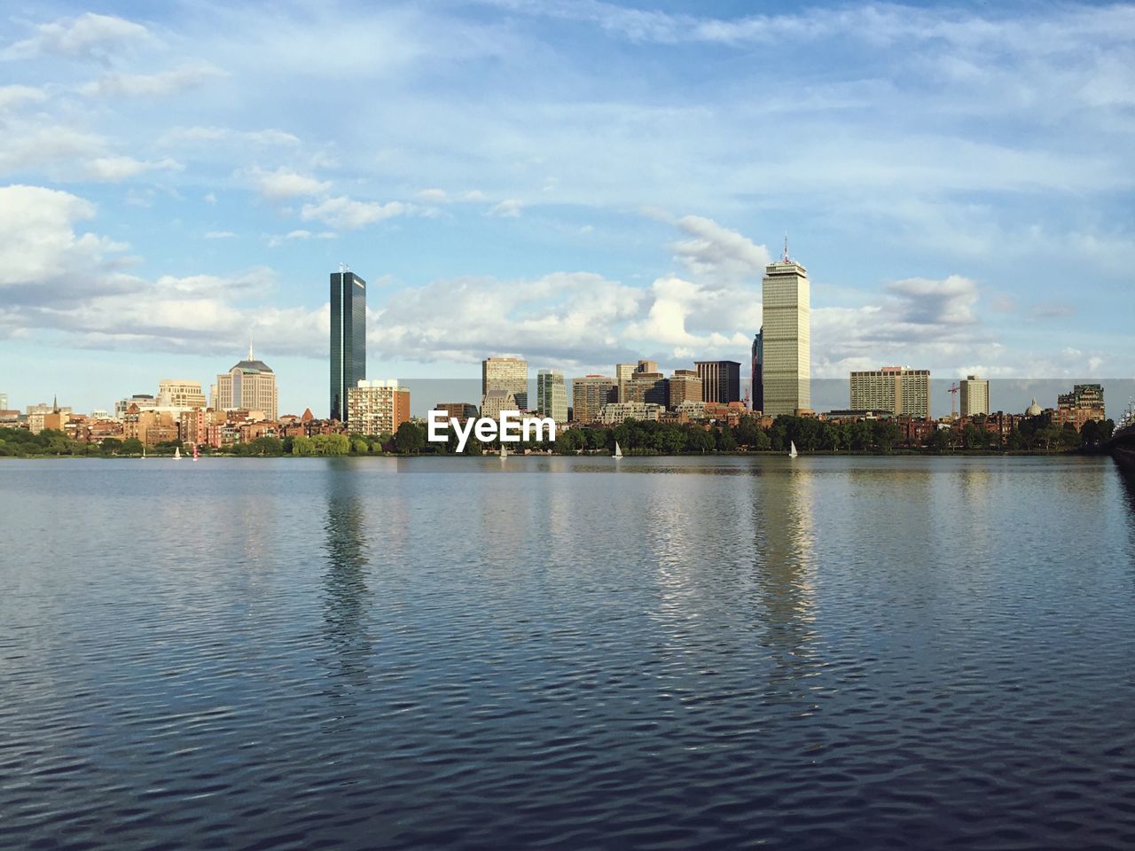 City at waterfront against cloudy sky