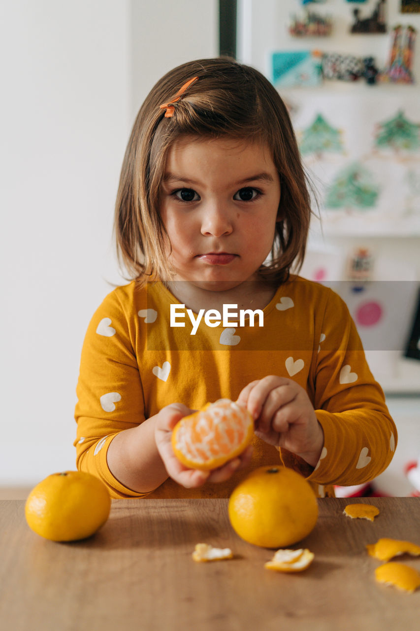 PORTRAIT OF CUTE GIRL HOLDING FRUITS