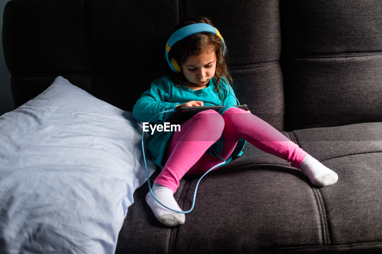 Young girl playing ipad game on a couch