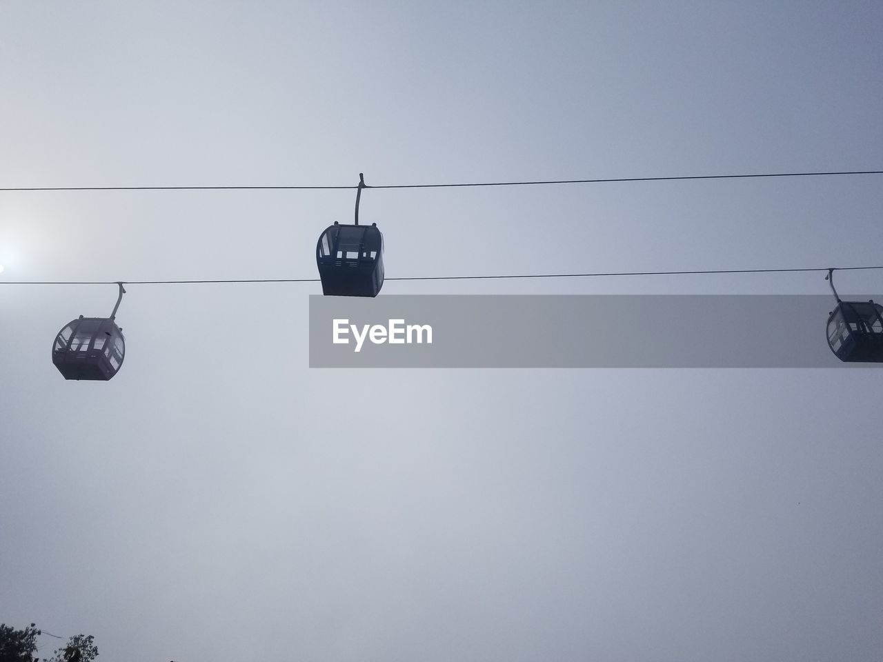 LOW ANGLE VIEW OF OVERHEAD CABLE CARS AGAINST SKY