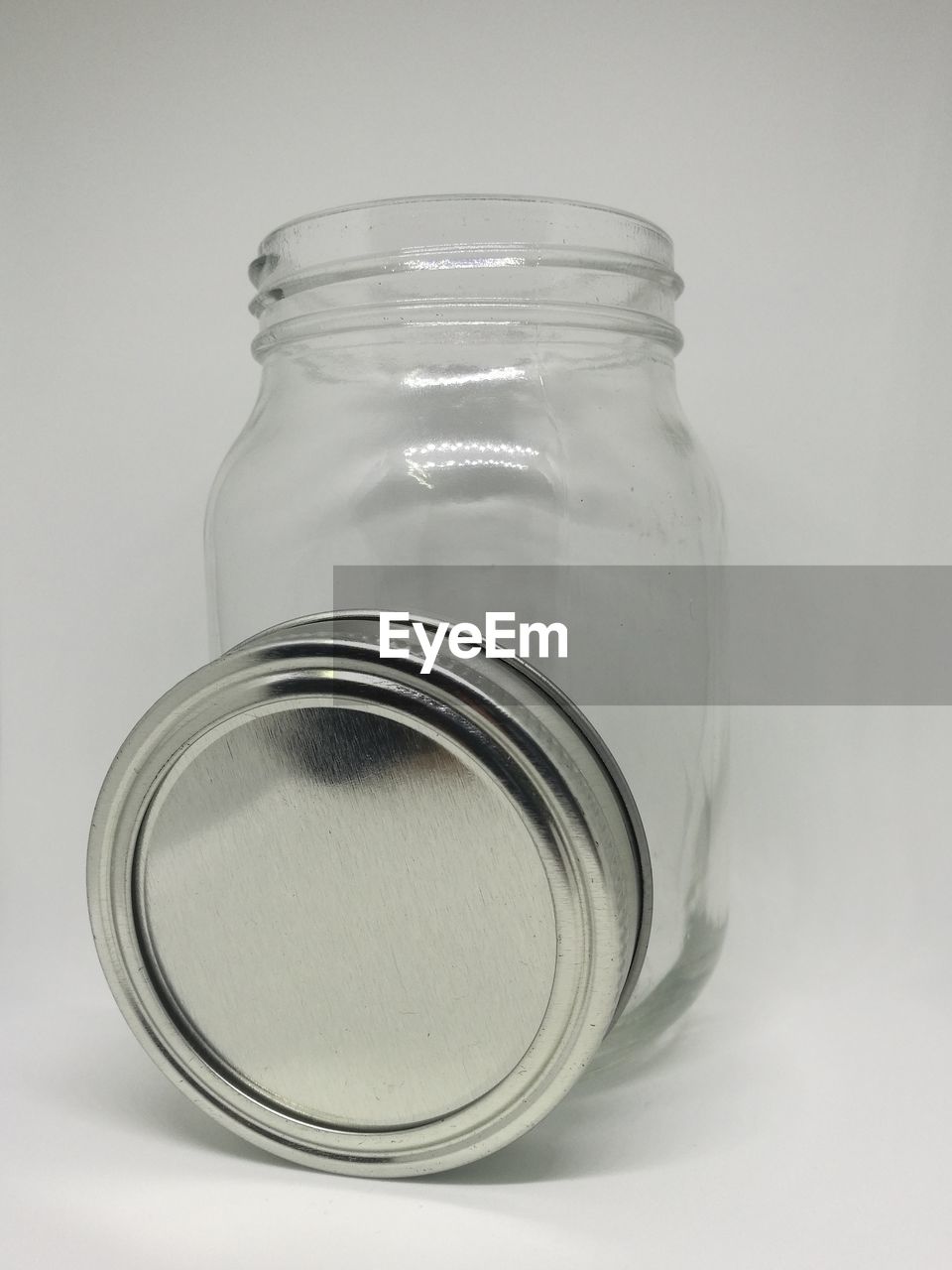 Close-up of jar and lid against white background
