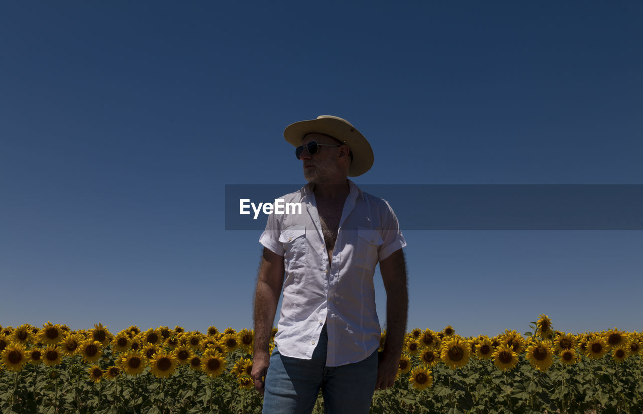 Adult man in cowboy hat and sunglasses in sunflowers fields. castilla y leon, spain