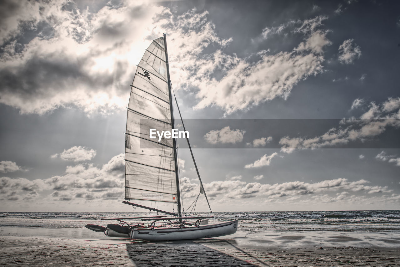 SAILBOAT SAILING ON SEA BY SHORE AGAINST SKY