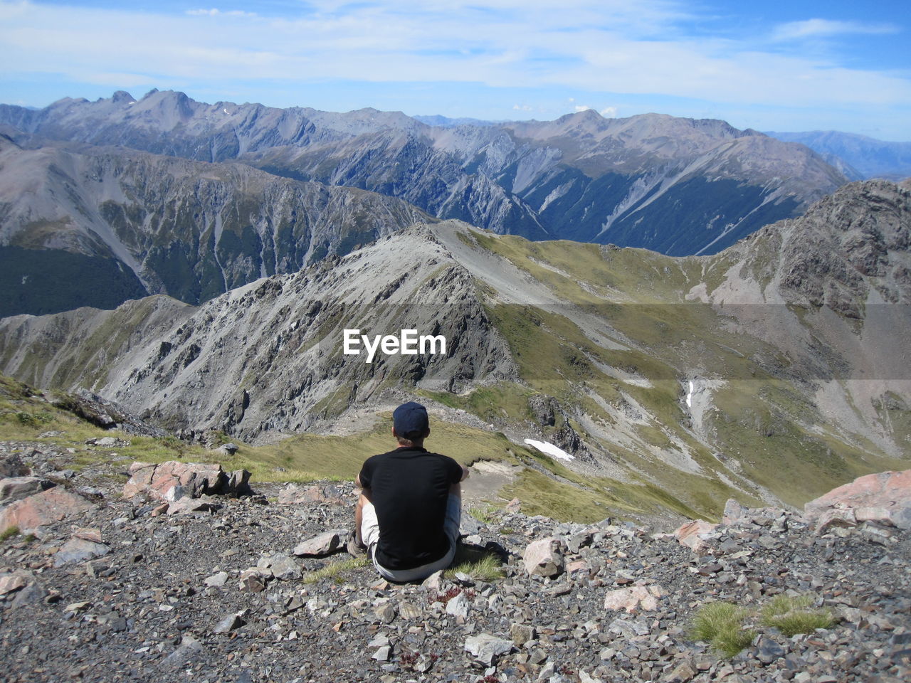 REAR VIEW OF WOMAN SITTING ON MOUNTAIN