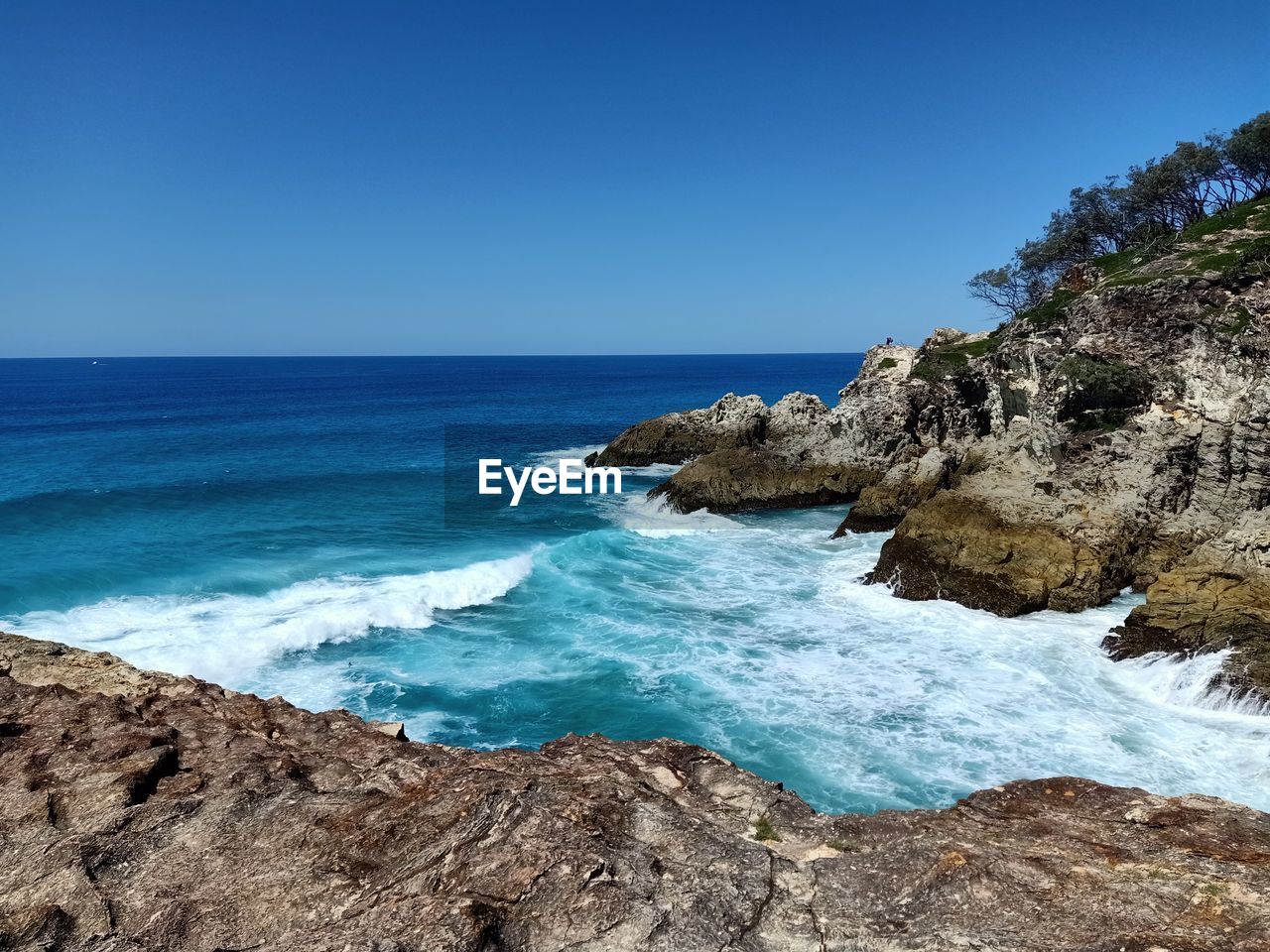 SCENIC VIEW OF ROCKY BEACH AGAINST CLEAR BLUE SKY