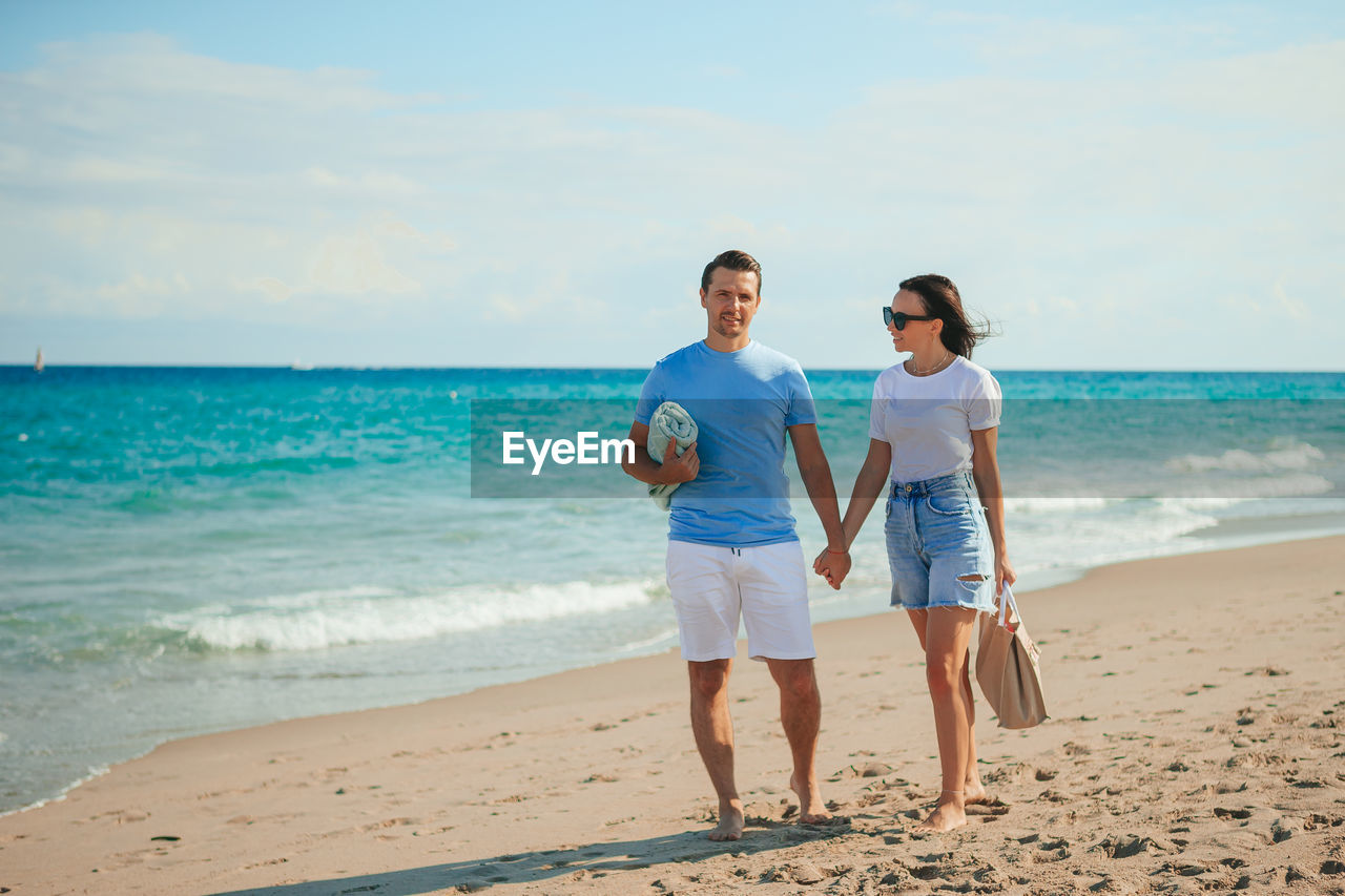 full length of couple standing at beach against sky