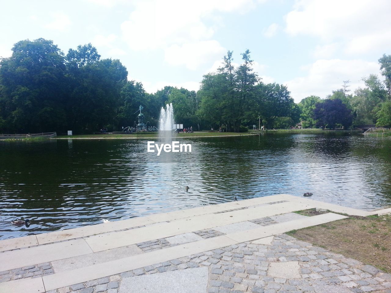 Scenic view of lake with fountain and trees against sky at stadtpark nurnberg