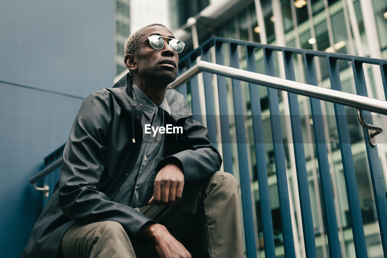 Stylish black man sitting on haunches on street