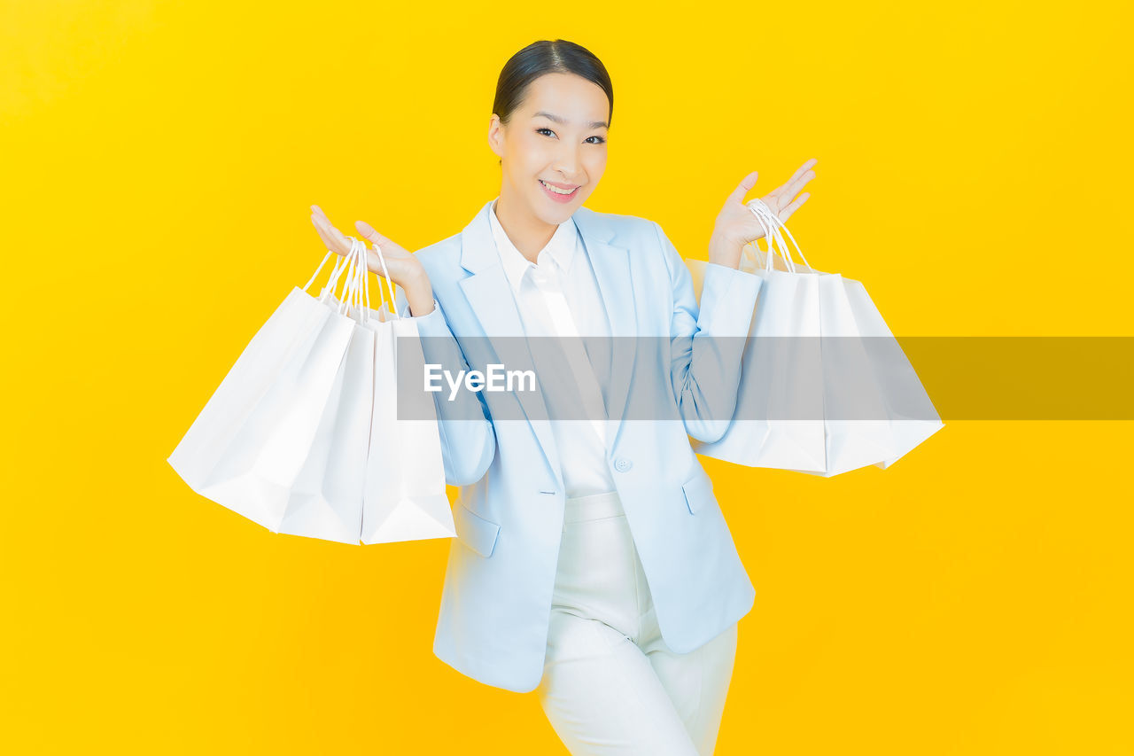 PORTRAIT OF SMILING YOUNG WOMAN HOLDING YELLOW UMBRELLA