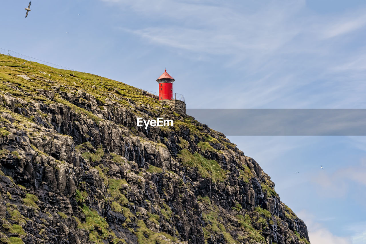 Low angle view of lighthouse on mountain against sky