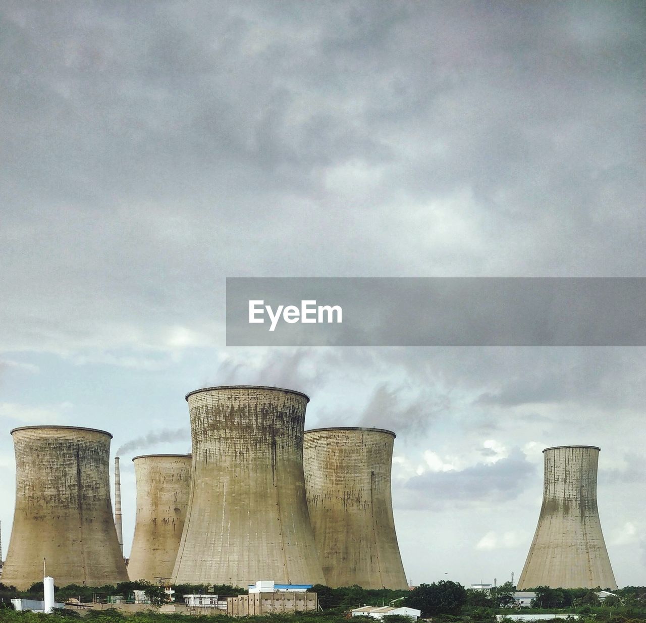 Low angle view of factory against cloudy sky