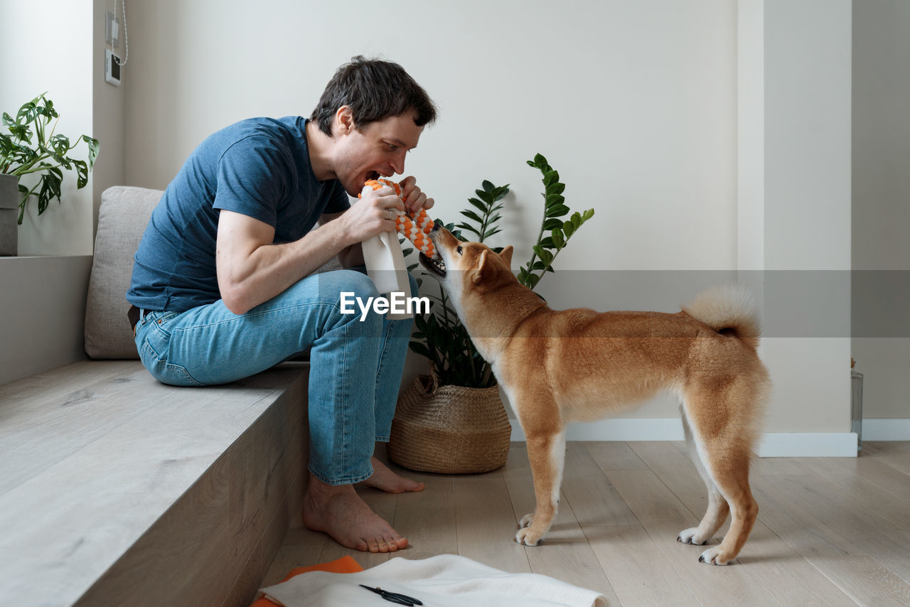 Funny adult man playing with a homemade dog toy with his favorite furry dog friend