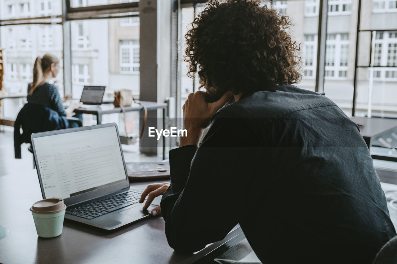 Businessman using laptop while sitting in coworking space