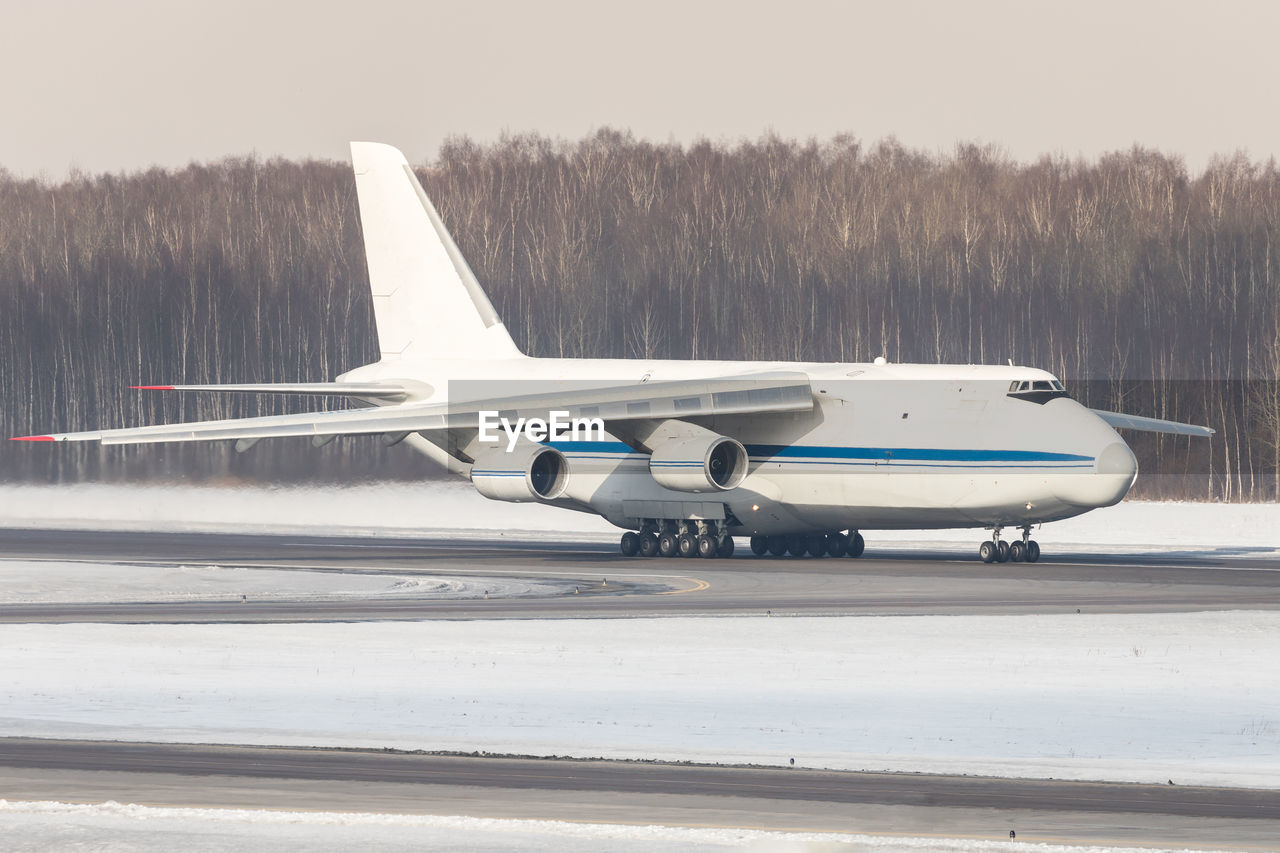 Huge white wide-body cargo airplane taxing on runway for take off at sunny winter day.