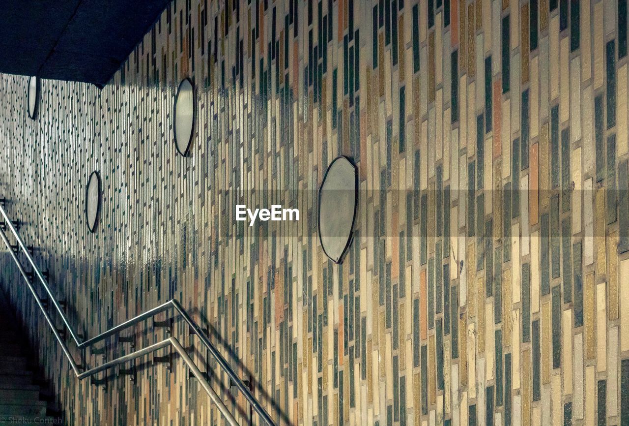 WOODEN WALL AND BUILDING SEEN THROUGH METAL RAILING