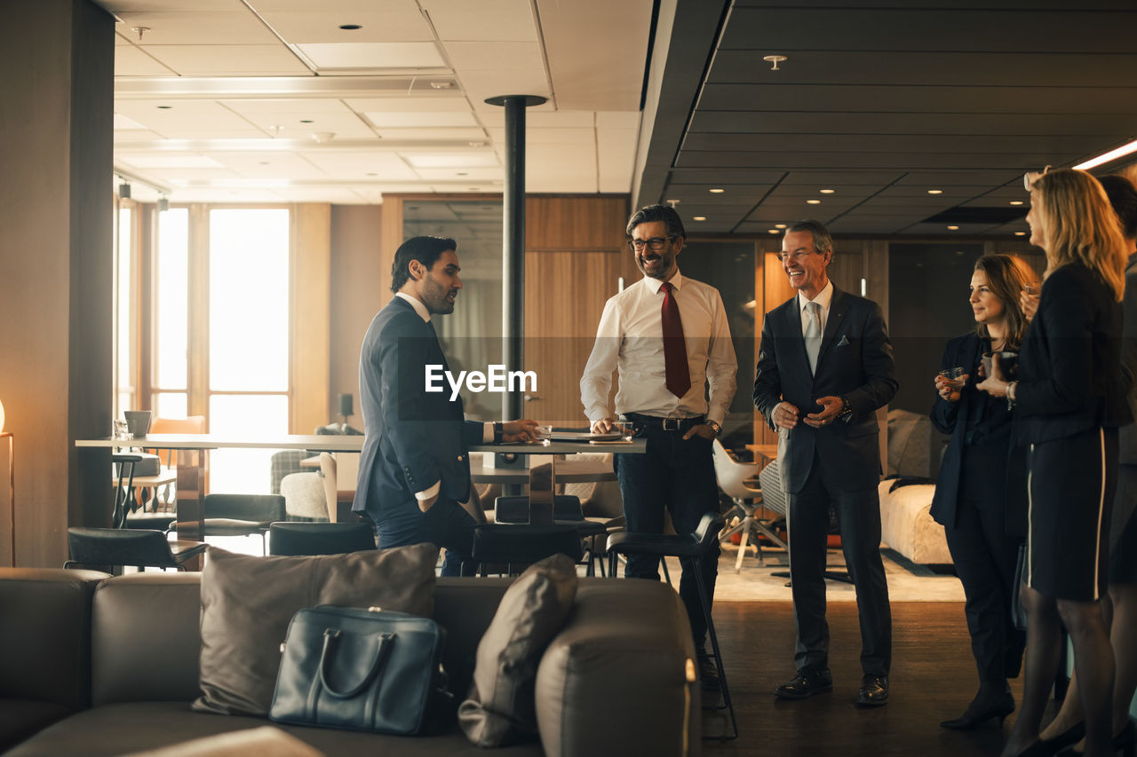 Smiling male and female lawyers communicating during coffee break at law office