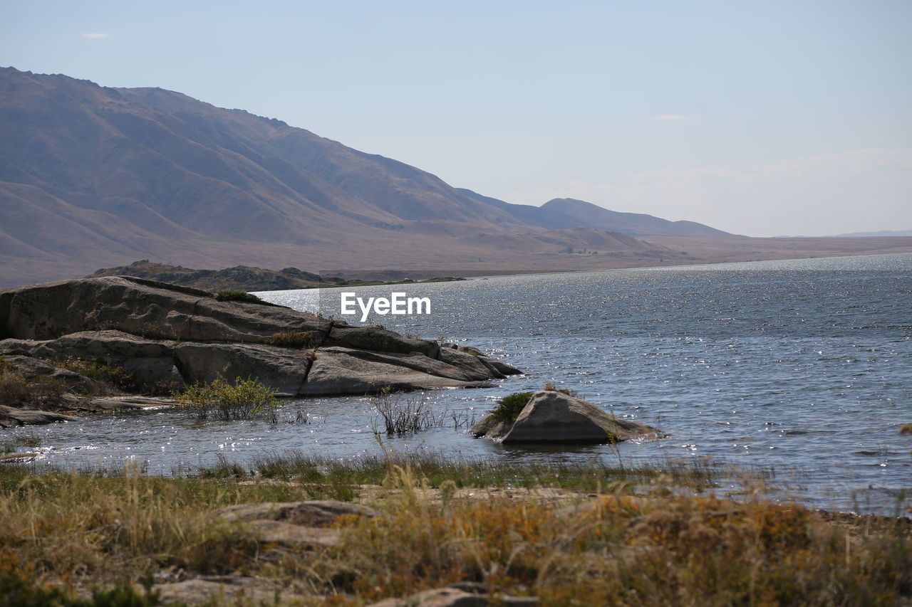 SCENIC VIEW OF SEA AGAINST MOUNTAINS