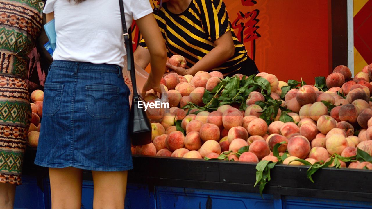 People buying peaches at market