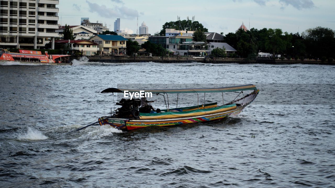 BOAT SAILING IN SEA BY BUILDINGS