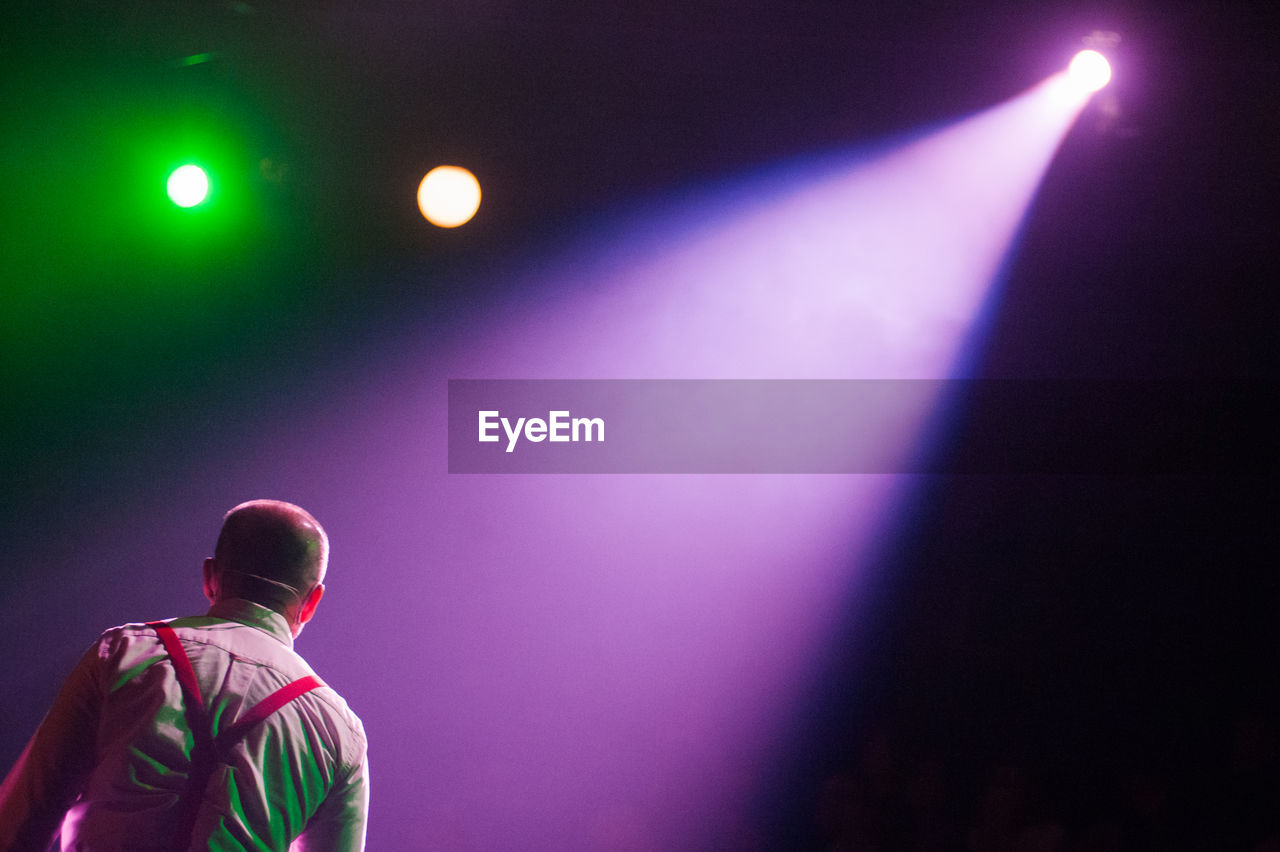 Illuminated spotlight falling on man during concert